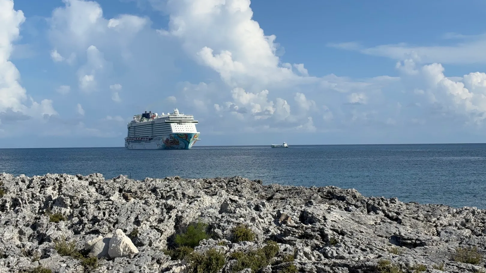 Cruise ship anchored beyond a rocky Caribbean shoreline